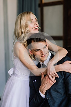 Cute wedding couple in the interior of a classic studio decorated. They kiss and hug each other.