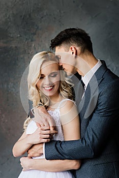 Cute wedding couple in the interior of a classic studio decorated. They kiss and hug each other.