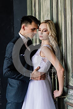 Cute wedding couple in the interior of a classic studio decorated. They kiss and hug each other.