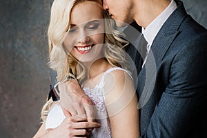 Cute wedding couple in the interior of a classic studio decorated. They kiss and hug each other.