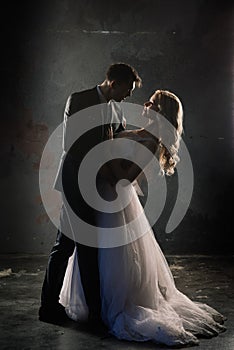 Cute wedding couple in the interior of a classic studio decorated. They kiss and hug each other.