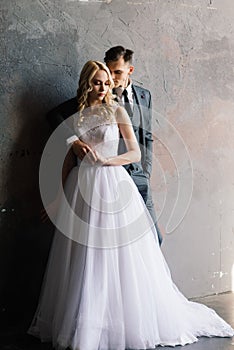 Cute wedding couple in interior of classic studio. They kiss and hug each other