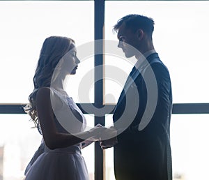 Cute wedding couple in interior of classic studio. They kiss and hug each other