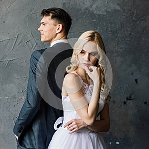 Cute wedding couple in interior of classic studio. They kiss and hug each other.