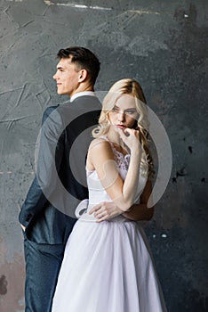 Cute wedding couple in interior of classic studio. They kiss and hug each other.