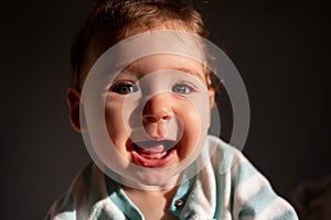 Cute white 9-month baby girl smile. Dark black background.