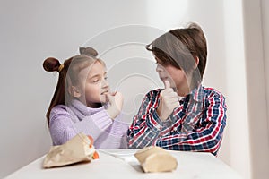 Cute white kids looking at each other while eating fries in a fast food restaurant. Couple of adorable elementary age children