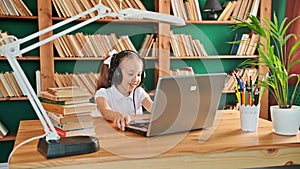 Cute white preteen girl school kid child pupil wearing headphones raising hand distance learning online talking to