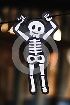Cute White skeleton bone hanging by black rope with bokeh blurred background, Halloween holiday festival