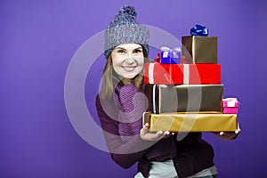 Cute Winsome Laughing Caucasian Adult Female in Seasonal Warm Clothing Posing with Big Wrapped Present Gift Boxes And Smiling