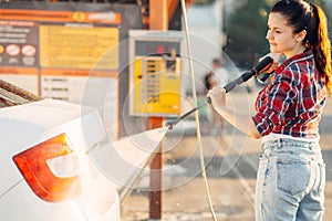 Cute woman with car washer on self service carwash