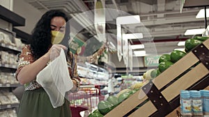 Cute woman choose fresh vegetables avocado grocery store. Young woman chooses in the grocery department of a supermarket