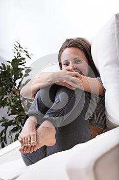 Cute woman curled up, bare toes pointed