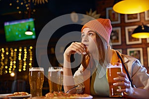 Cute woman football fan watching TV match in sports bar