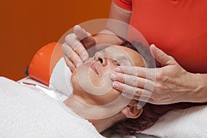 Cute woman gets professional facial massage, lymphatic drainage