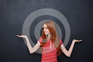 Cute woman holding copyspace on two palms over blackboard background