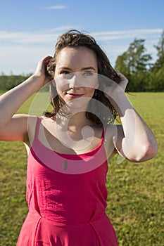 Cute woman holding hair in sunny meadow