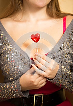 Cute woman holding red decorative heart on stick