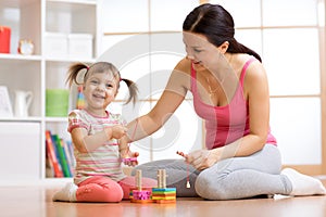 Cute woman and kid girl playing educational toys at home