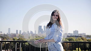 A cute woman is looking at the camera, she is sightseeing landscape view of Warsaw city, Poland