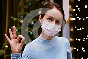 cute woman in a medical mask shows with a gesture that everything is fine