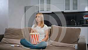 Cute woman relaxing and watching TV with popcorn at home.