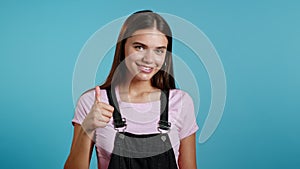 Cute woman showing thumb up sign over blue background. Positive young girl smiles to camera. Winner. Success. Body