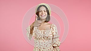 Cute woman showing thumb up sign over pink background. Positive young girl smiles to camera. Winner. Success. Body