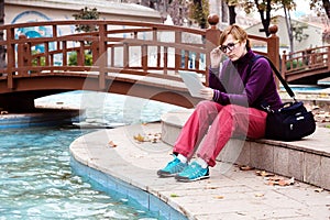 Cute Woman sitting in Park using tablet device