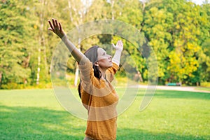 Cute woman standing in spring nature park with wide open arms raised up