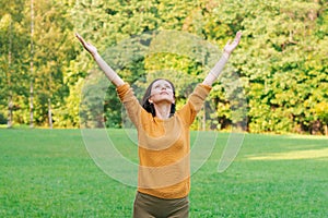 Cute woman standing in spring nature park with wide open arms raised up