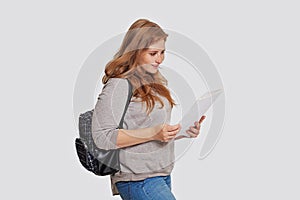 Cute woman student with backpack and lecture notes paper against white studio wall banner background