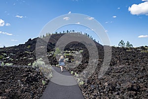 Cute woman takes a hike along the Trail of Molten Lands in Lava Lands Newberry Volcano National Monument in Oregon