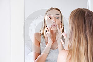 Cute woman touching her lips while looking in the mirror, beauty and skin care concept,wrinkles
