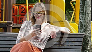 Cute woman using voice command recorder on smartphone at city playground outdoor