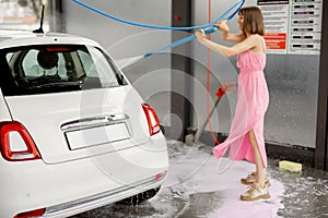 Cute woman washes her vehicle at self-service car wash