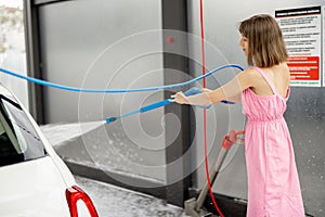 Cute woman washes her vehicle at self-service car wash