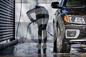 Cute woman washing her car in a manual carwash