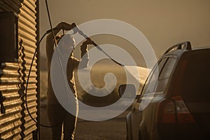 Cute woman washing her car in a manual carwash