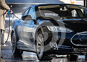 Cute woman washing her car in a manual carwash