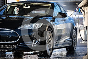 Cute woman washing her car in a manual carwash