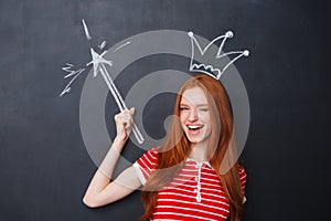 Cute woman winking with crown and magic wand over chalkboard