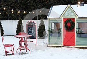 Cute wooden painted red-green private children play house in home garden, decorated with Christmas wreath outdoors in