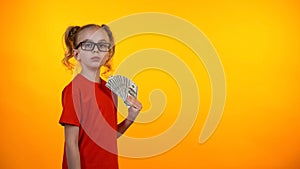 Cute wunderkind girl holding bunch of dollar cash, nerd winning grant, income