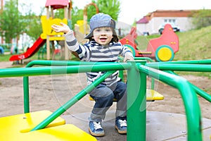 Cute 2 years boy on merry-go-round outdoors