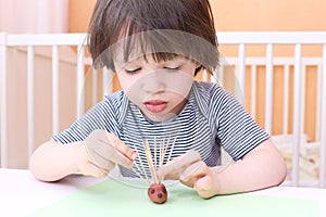 Cute 2 years child made toothpick spines by playdough hedgehog a photo