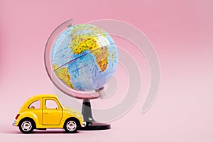 Cute yellow little retro car with world globe sphere. Travel concept. Planning summer vacations