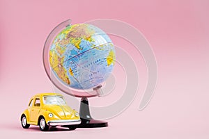 Cute yellow little retro car with world globe sphere. Travel concept. Planning summer vacations