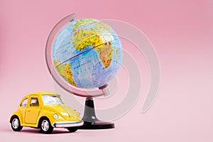 Cute yellow little retro car with world globe sphere. Travel concept. Planning summer vacations