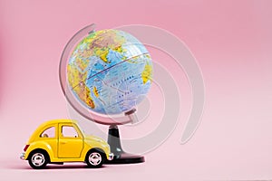 Cute yellow little retro car with world globe sphere. Travel concept. Planning summer vacations